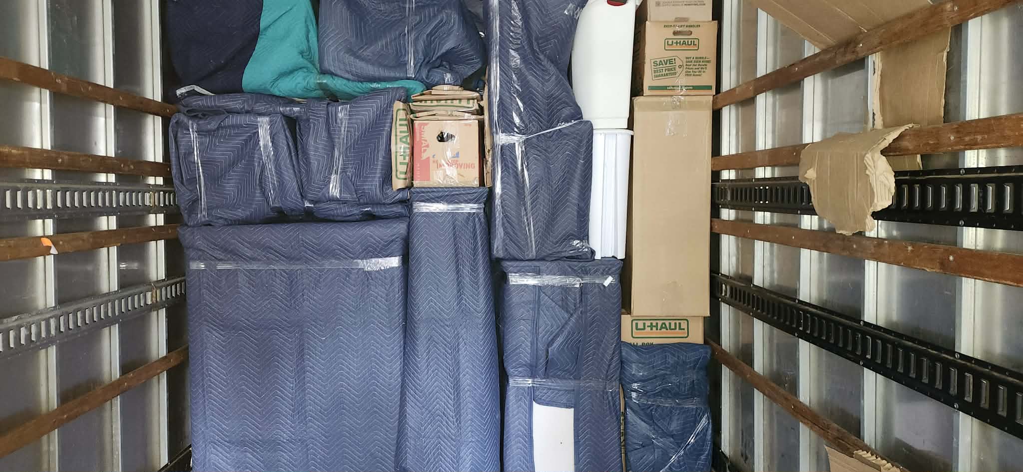 Furniture carefully wrapped in moving blankets inside truck