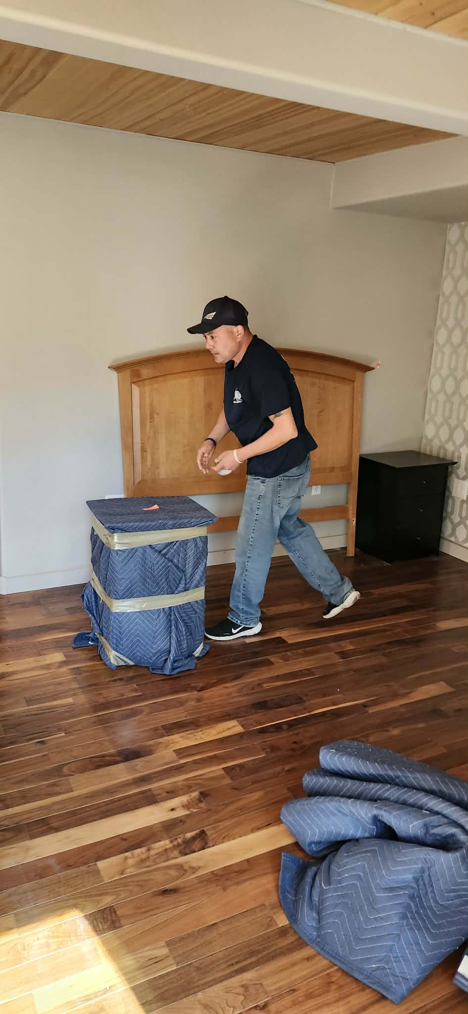 Chris Adams carefully moving wrapped furniture in a client's home