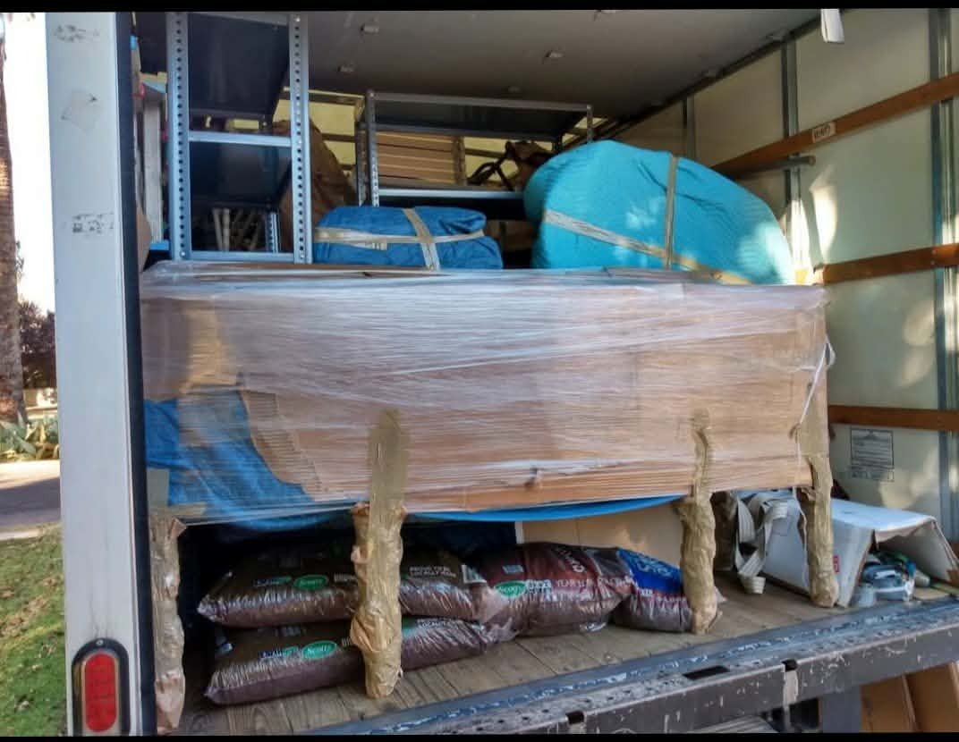 Furniture wrapped in protective plastic and moving blankets inside truck