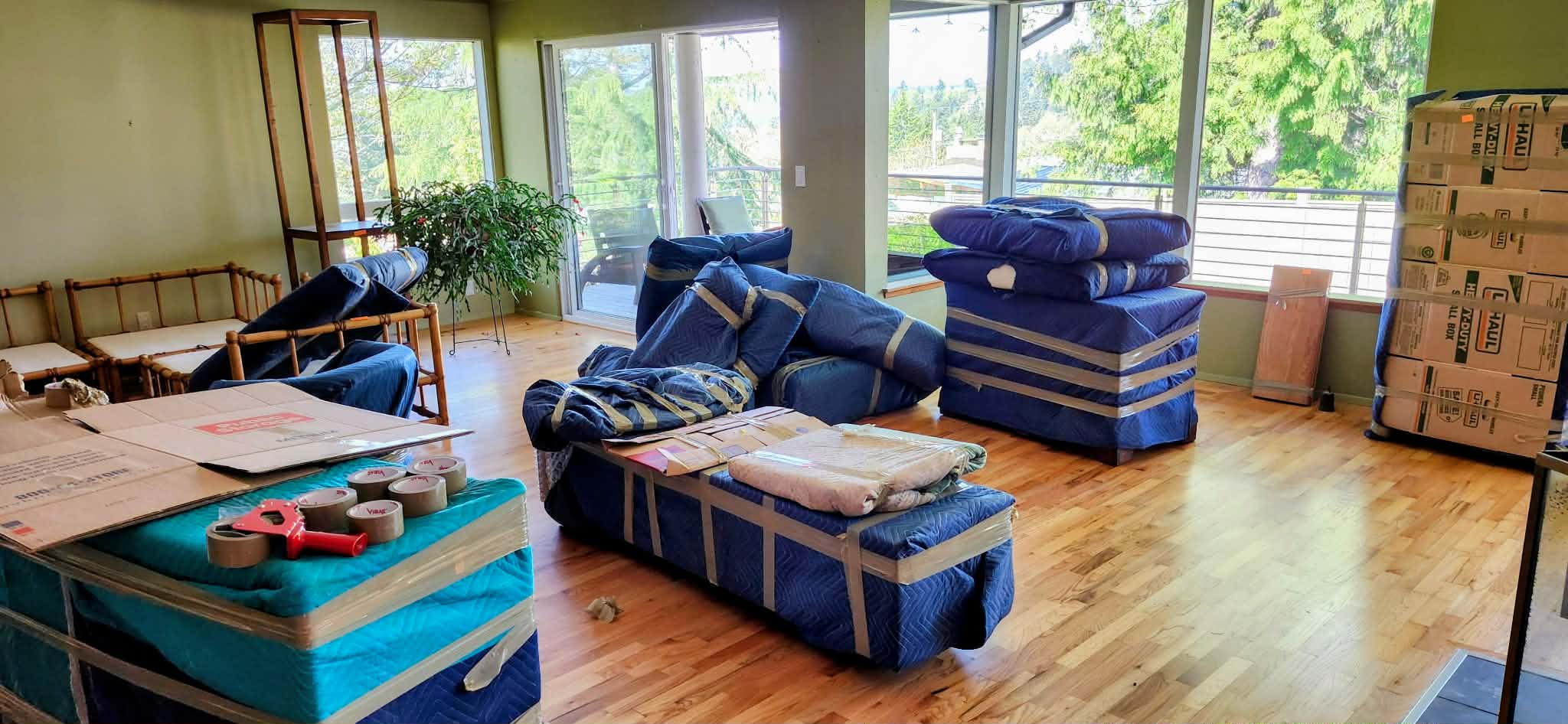 Living room with all furniture wrapped in protective blue moving blankets